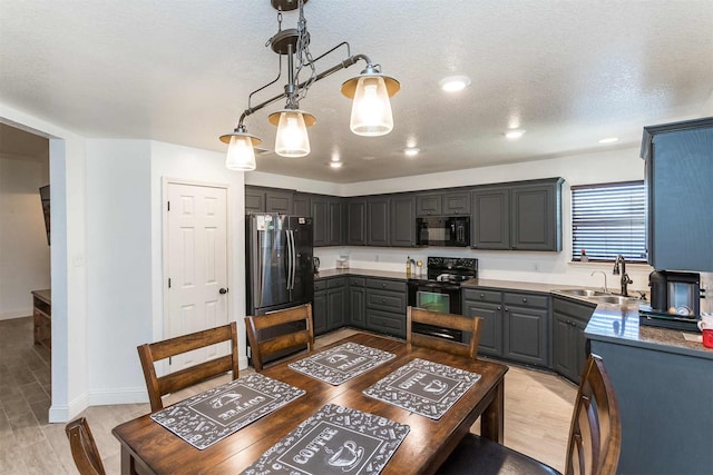 kitchen with a textured ceiling, black appliances, sink, gray cabinetry, and light hardwood / wood-style floors