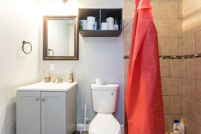 bathroom with walk in shower, toilet, and vanity