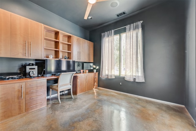 home office with ceiling fan, built in desk, and concrete flooring