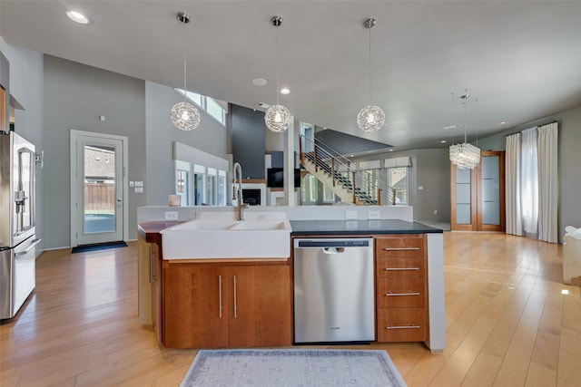 kitchen with sink, hanging light fixtures, stainless steel appliances, an inviting chandelier, and a kitchen island with sink