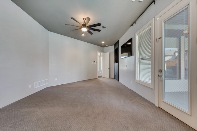 empty room with ceiling fan and light carpet