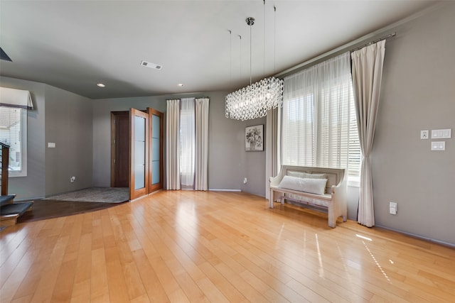 unfurnished room featuring an inviting chandelier and light hardwood / wood-style flooring