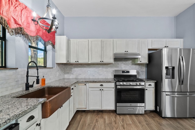 kitchen with dark wood-type flooring, white cabinets, appliances with stainless steel finishes, and light stone counters