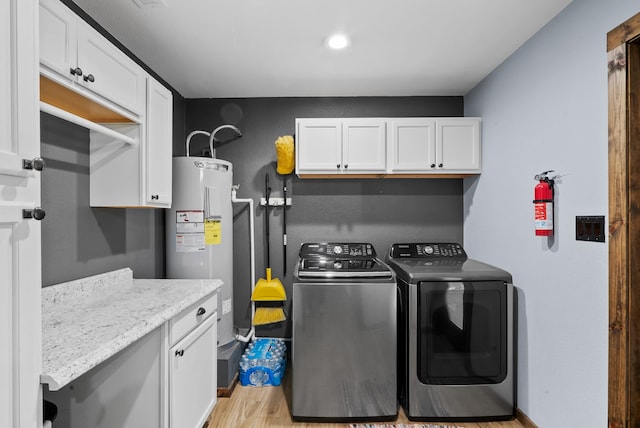 clothes washing area with light wood-type flooring, cabinets, washer and dryer, and water heater