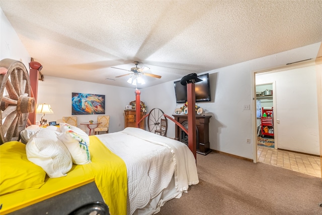 bedroom with a walk in closet, ceiling fan, carpet floors, and a textured ceiling