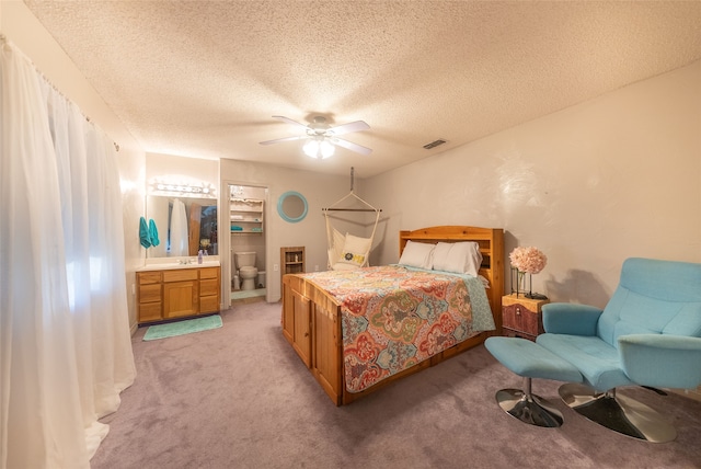 bedroom with carpet flooring, ceiling fan, connected bathroom, and a textured ceiling