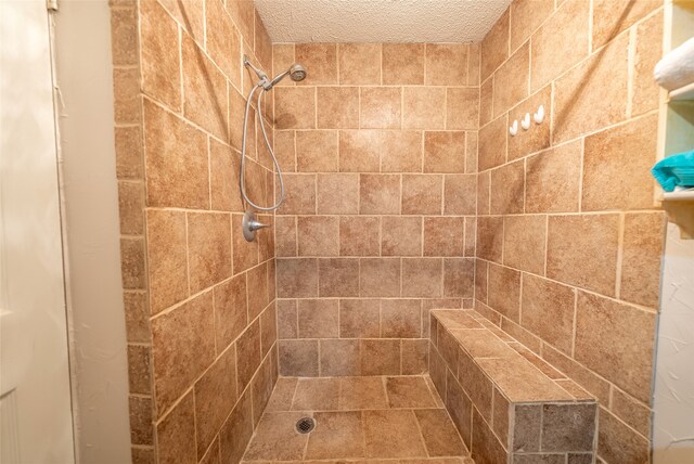 bathroom with a textured ceiling and a tile shower