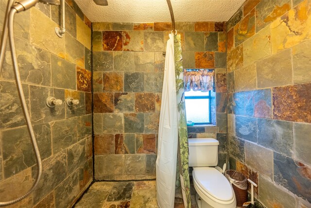 bathroom featuring a textured ceiling, tile walls, a shower with curtain, and toilet