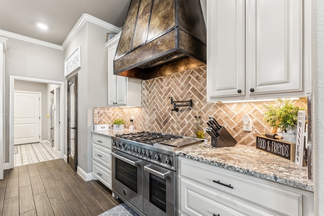 kitchen featuring custom range hood, white cabinetry, tasteful backsplash, range with two ovens, and crown molding