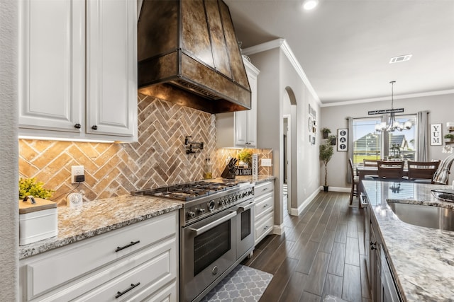 kitchen featuring dark wood-type flooring, white cabinetry, custom exhaust hood, decorative light fixtures, and double oven range