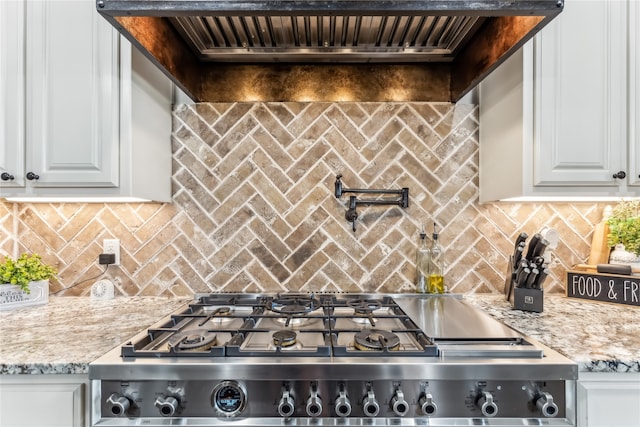 kitchen with white cabinets, light stone counters, and stainless steel range oven