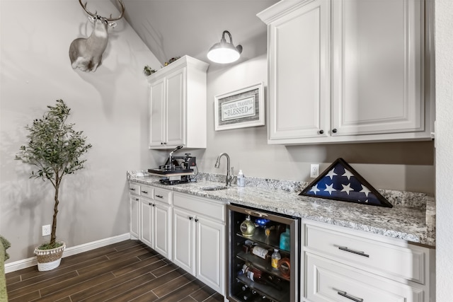 bar with beverage cooler, white cabinetry, sink, and dark hardwood / wood-style flooring