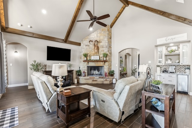 living room featuring a stone fireplace, beamed ceiling, dark hardwood / wood-style floors, and high vaulted ceiling