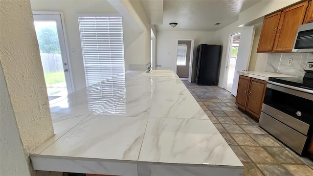 kitchen featuring light stone counters, stainless steel appliances, sink, and a healthy amount of sunlight