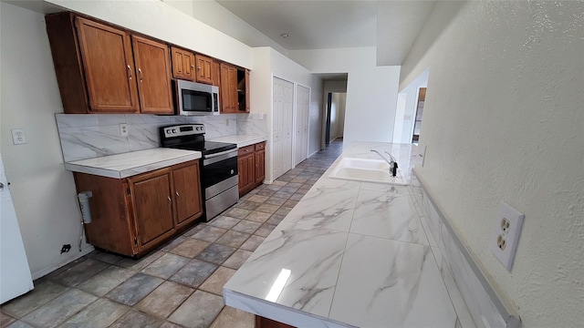 kitchen with appliances with stainless steel finishes, backsplash, and sink