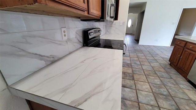 kitchen featuring stainless steel electric stove and tasteful backsplash