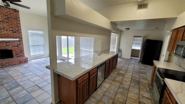 kitchen featuring appliances with stainless steel finishes, a fireplace, sink, and ceiling fan