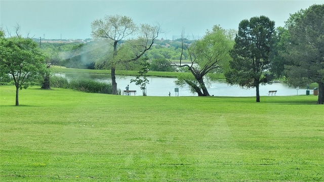 view of property's community with a water view and a lawn