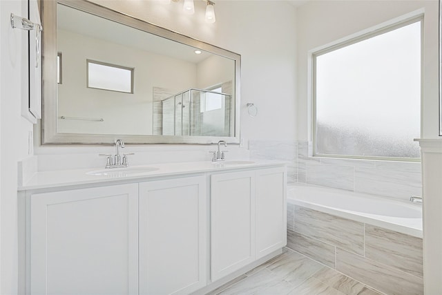 bathroom featuring plus walk in shower, vanity, and a wealth of natural light