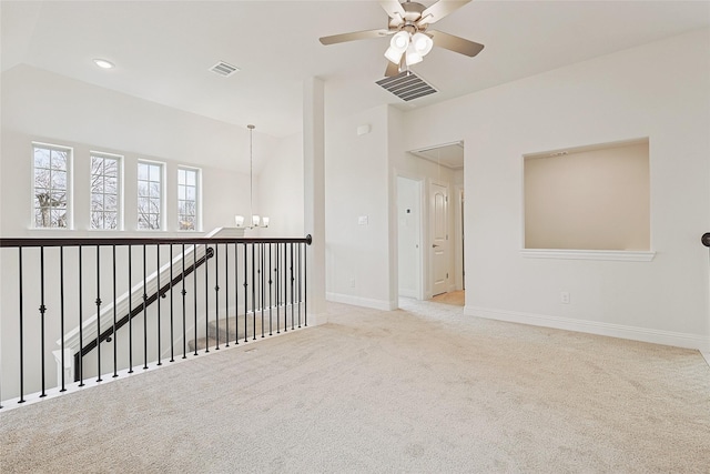 carpeted empty room with ceiling fan with notable chandelier