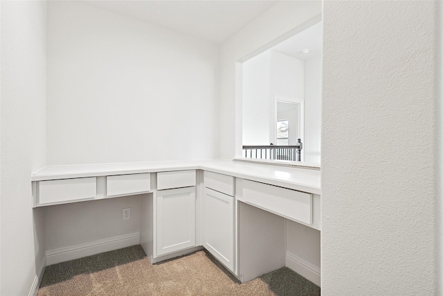 unfurnished office with light colored carpet and built in desk