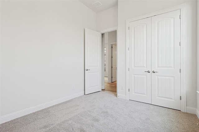 unfurnished bedroom with a closet and light colored carpet