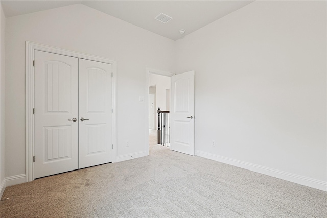 unfurnished bedroom with carpet flooring, a closet, and lofted ceiling