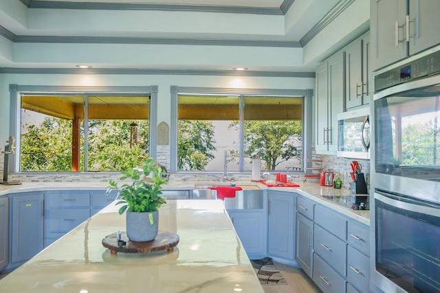 kitchen with ornamental molding, plenty of natural light, stainless steel appliances, and light stone countertops