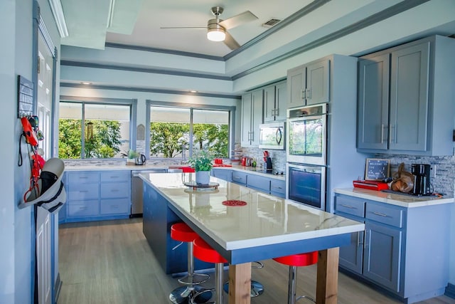 kitchen with a healthy amount of sunlight, stainless steel appliances, a center island, ceiling fan, and a breakfast bar area