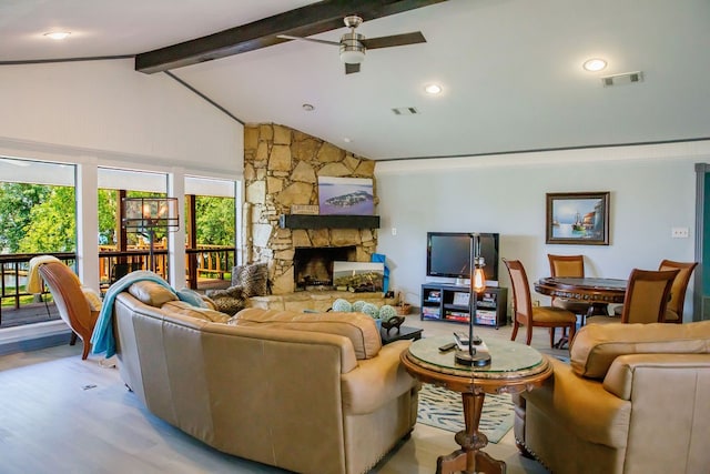 living room with ceiling fan, wood-type flooring, lofted ceiling with beams, and a stone fireplace