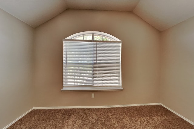 carpeted spare room featuring vaulted ceiling