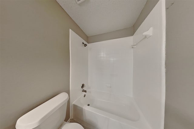 bathroom featuring bathtub / shower combination, toilet, and a textured ceiling