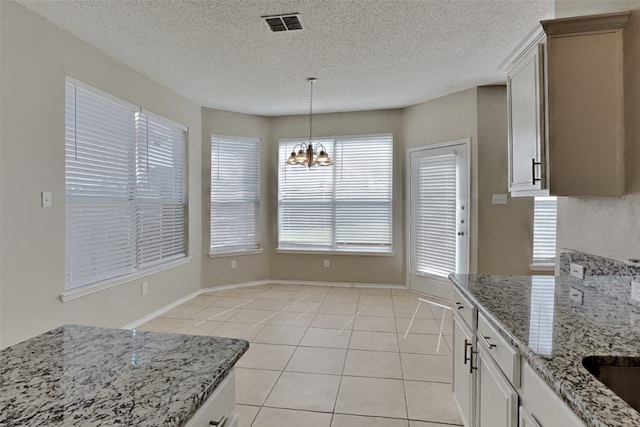 kitchen with a wealth of natural light, white cabinetry, and a notable chandelier