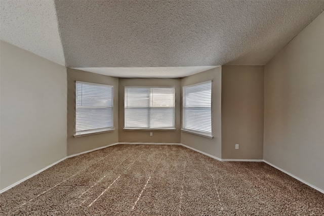 carpeted empty room featuring a textured ceiling