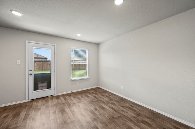 spare room featuring a textured ceiling and dark wood-type flooring