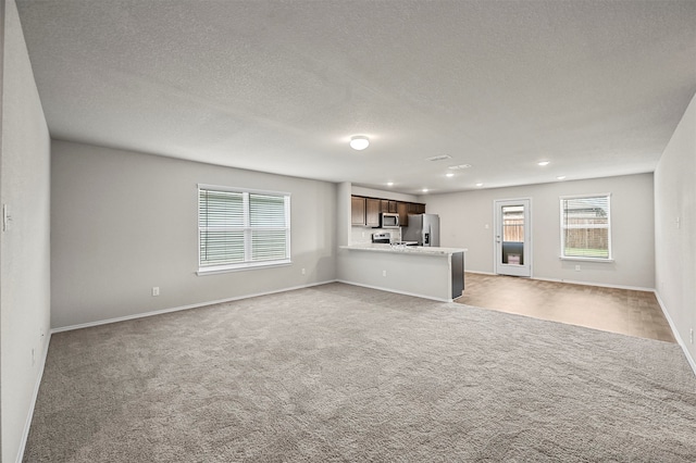 unfurnished living room featuring light colored carpet and a textured ceiling