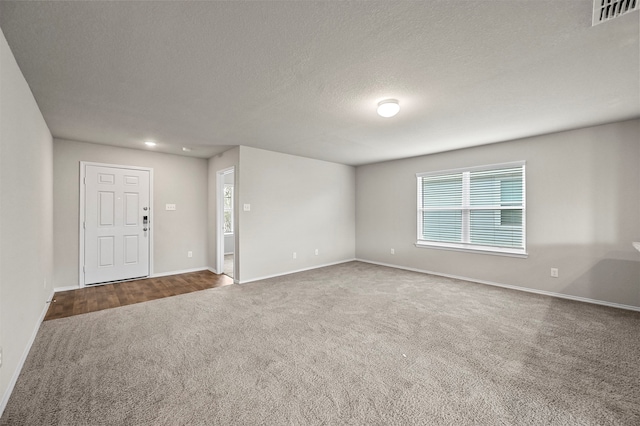 carpeted empty room with a textured ceiling