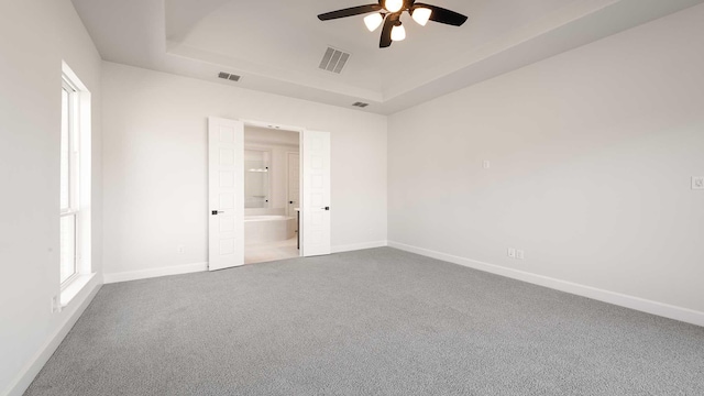 carpeted empty room featuring ceiling fan and a raised ceiling