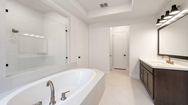 bathroom with vanity, tiled bath, and a tray ceiling