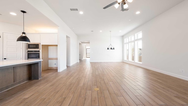 kitchen with light hardwood / wood-style floors, black microwave, plenty of natural light, and stainless steel oven