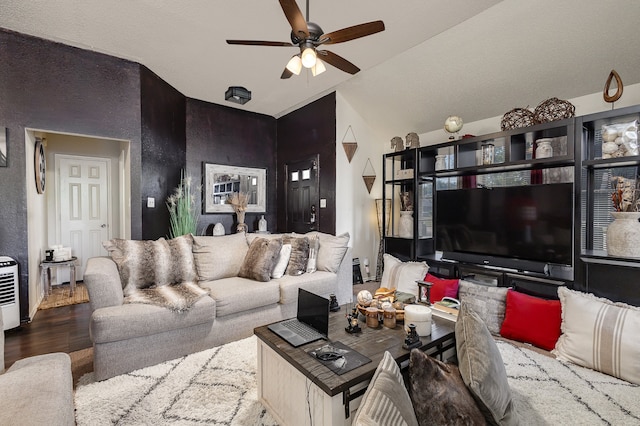 living room with hardwood / wood-style flooring, ceiling fan, and vaulted ceiling