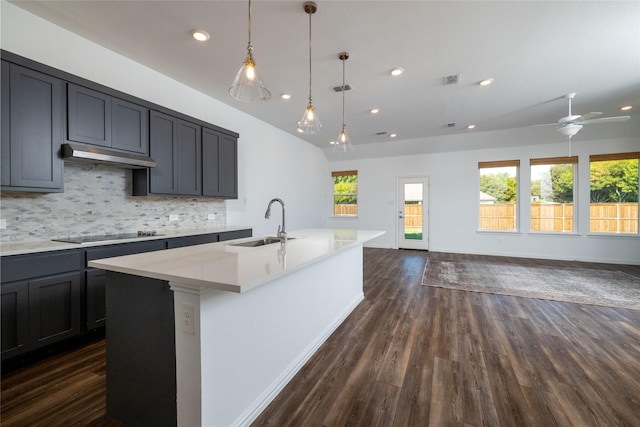 kitchen featuring sink, ceiling fan, black electric stovetop, a center island with sink, and decorative backsplash