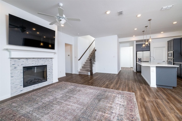 unfurnished living room with dark hardwood / wood-style flooring, sink, a tile fireplace, and ceiling fan