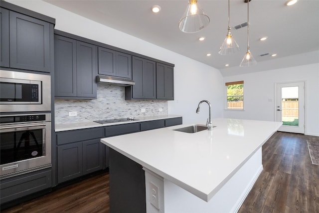 kitchen featuring stainless steel appliances, sink, a kitchen island with sink, and decorative backsplash