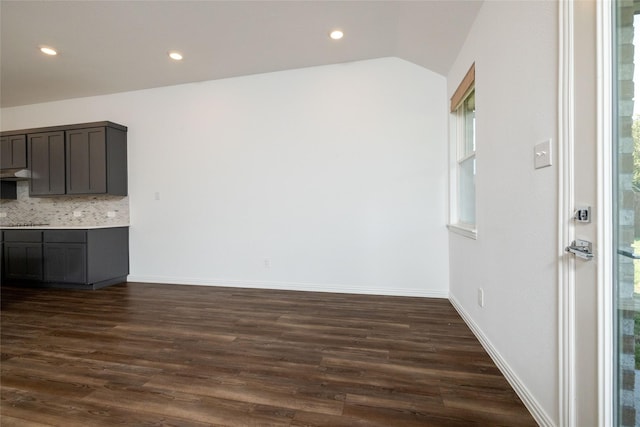 interior space featuring lofted ceiling, backsplash, dark hardwood / wood-style floors, dark brown cabinetry, and black electric cooktop