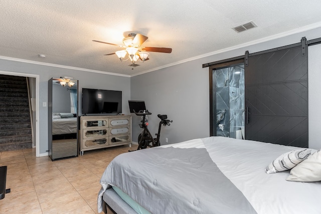 bedroom featuring a textured ceiling, a barn door, light tile patterned flooring, ceiling fan, and ornamental molding