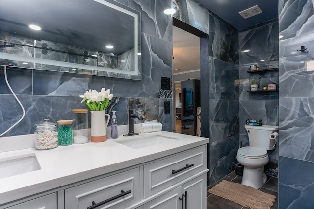 bathroom featuring vanity, toilet, tile walls, and tile patterned flooring