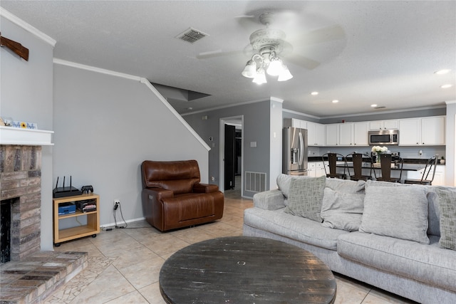 tiled living room with crown molding, a textured ceiling, ceiling fan, and a stone fireplace