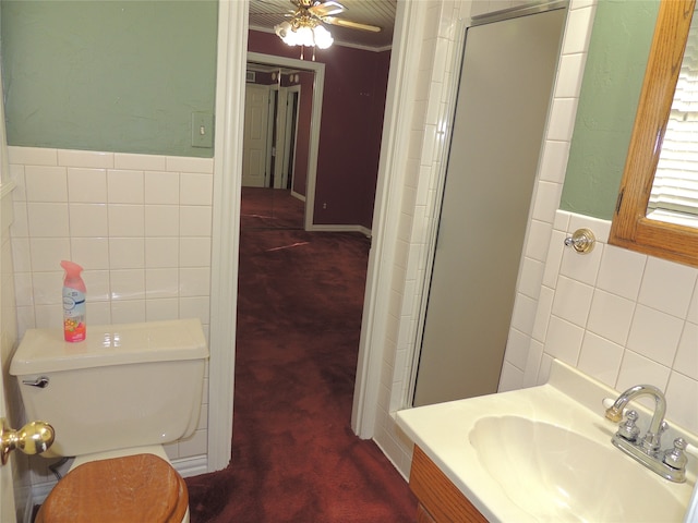 bathroom featuring ceiling fan, an enclosed shower, toilet, vanity, and tile walls