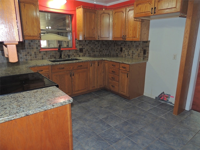 kitchen with decorative backsplash, sink, black stove, and light stone counters